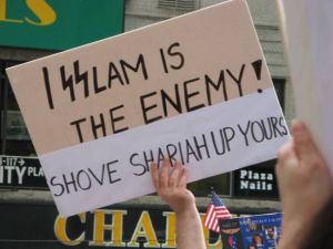 Islam Protest Sign: "Islam is the Enemy - Shove Shariah Up Yours"
