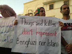 A Libyan woman holds a sign that reads "Thugs and killers don't represent Benghazi nor Islam"